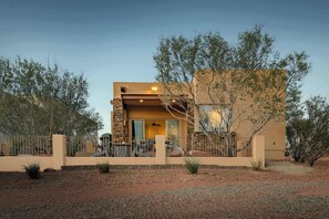 A modern two-story building with a stone facade, a flat roof, and a fenced patio area.