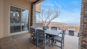 Une terrasse extérieure avec une table et des chaises, un pot de fleurs et une vue sur un paysage désertique.