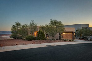 A modern two-story house with a garage, surrounded by landscaped gardens and a view of the desert landscape. - [The Ridgeview] 50 Mile Views (Page)