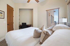 A hotel room with a bed, a desk, a chair, a wardrobe, and a window with blinds.