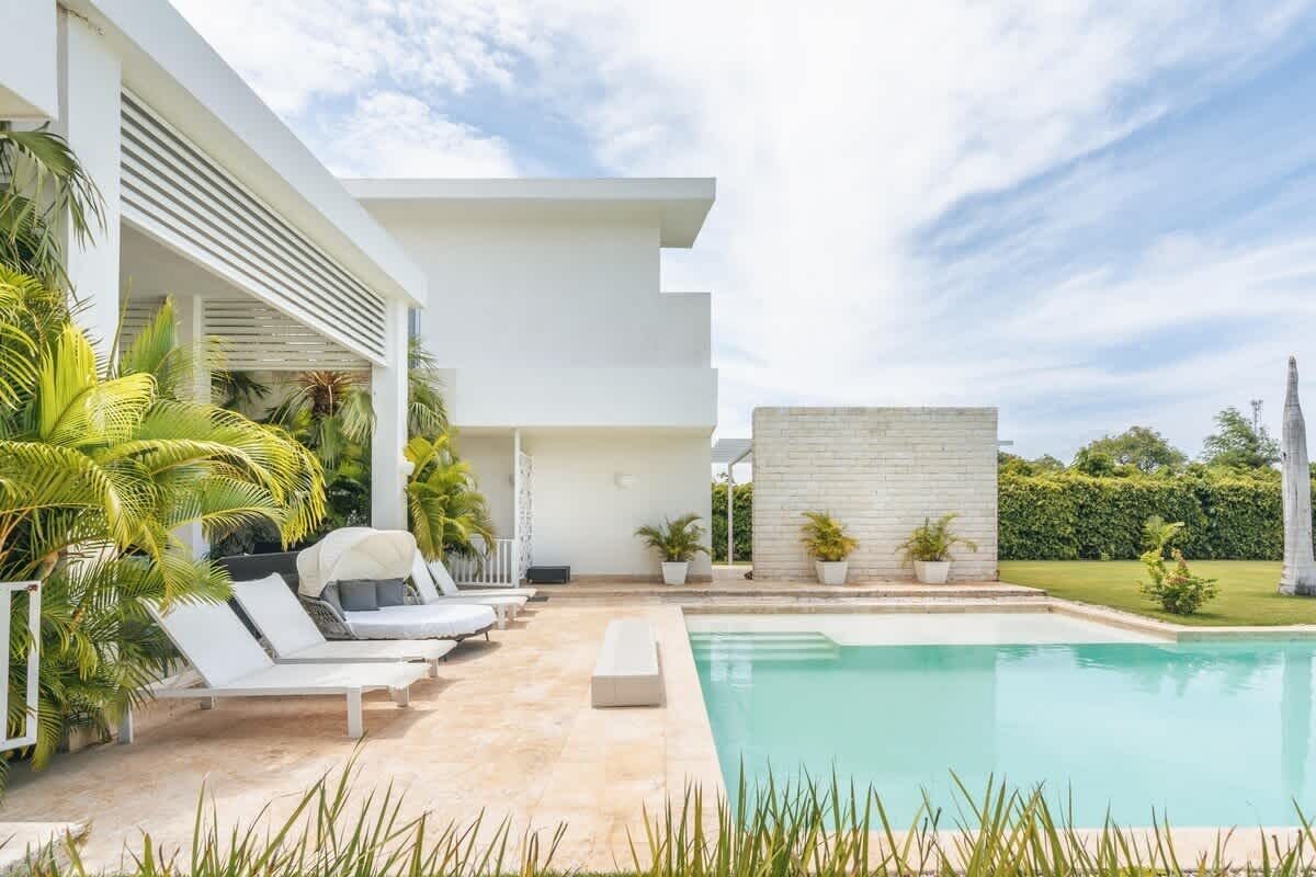 A modern poolside area with lounge chairs, a pool, and potted plants.