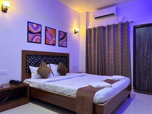 A hotel room with a bed, a nightstand, a phone, and a wall-mounted air conditioner.