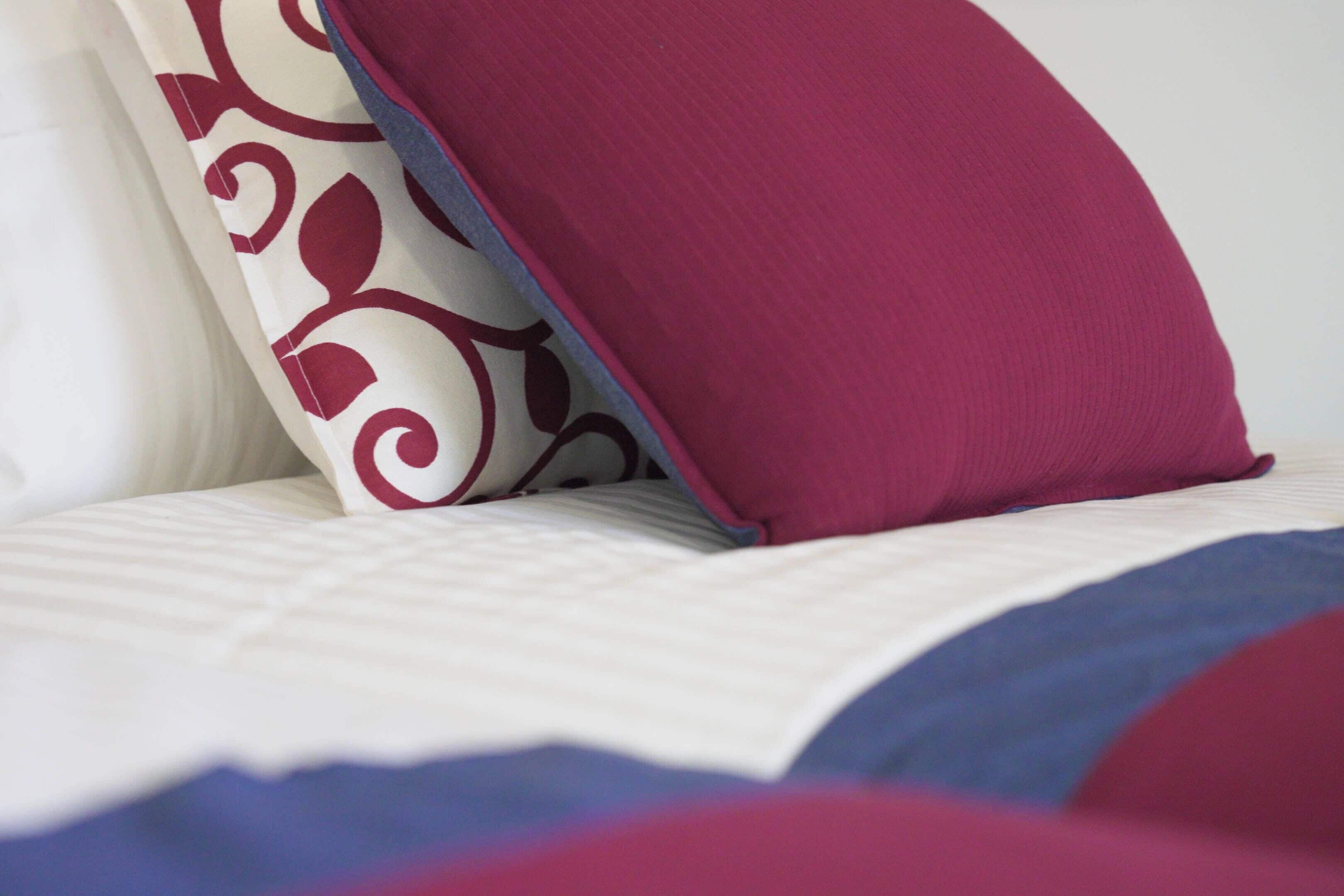 Ein Bett mit einem gemusterten Kopfkissen und einem einfarbigen Kopfkissen.