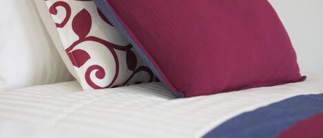 Un lit avec un oreiller à motifs et un oreiller d’une couleur unie.