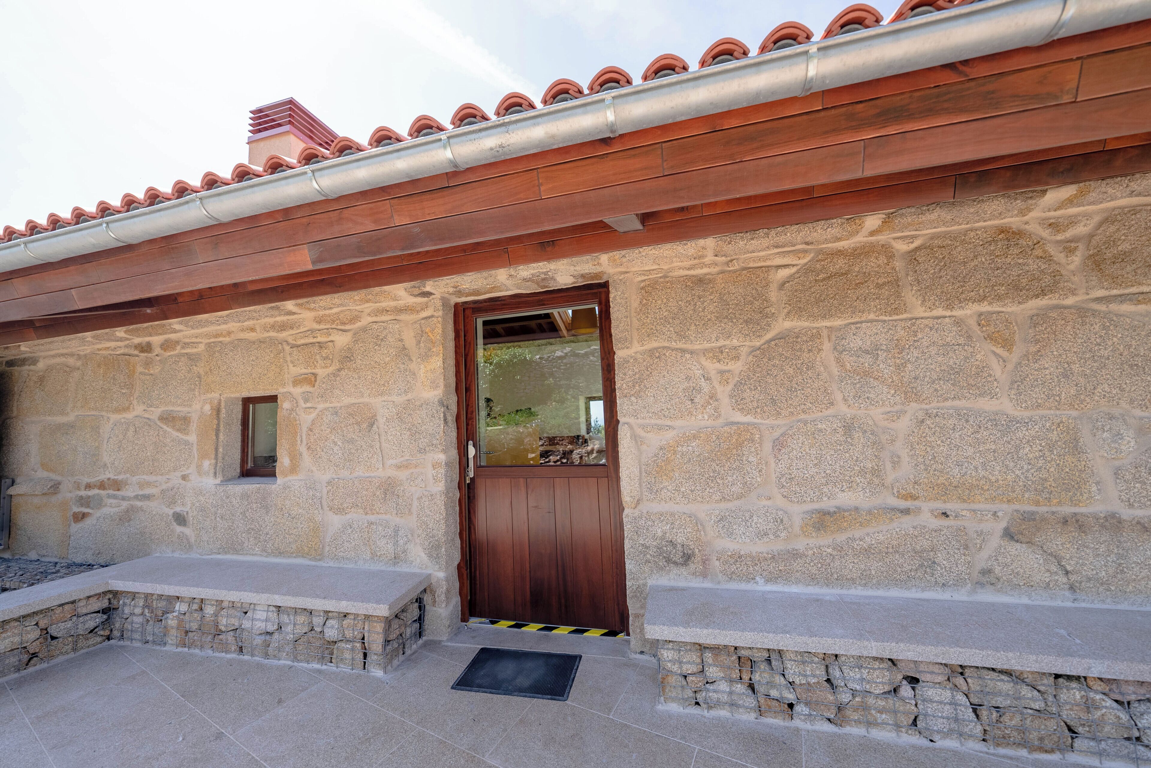 Un edificio de piedra con puerta de madera, escalones de piedra y techo de tejas.
