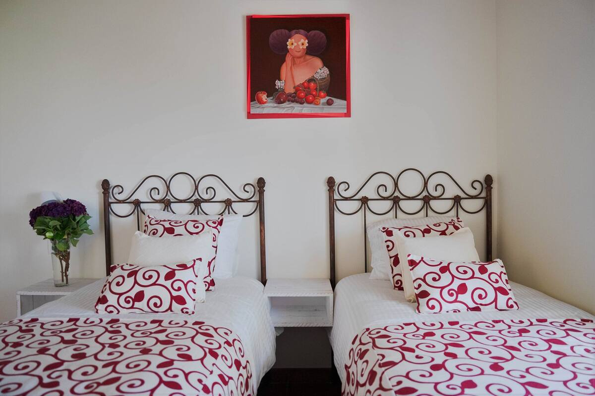 A double bed with a metal frame and red and white patterned bedding.