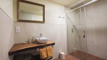 A bathroom with a wooden vanity, a white sink, a mirror, and a glass shower enclosure.
