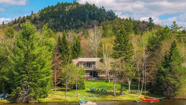 A lakeside lodge with a dock, kayaks, and a lawn with outdoor seating. - Lake Cottage | 5 Bed, 5 Bath (Lake Placid)