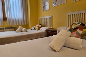 Een hotelkamer met twee bedden, een radiator en kunstwerken aan de wanden.