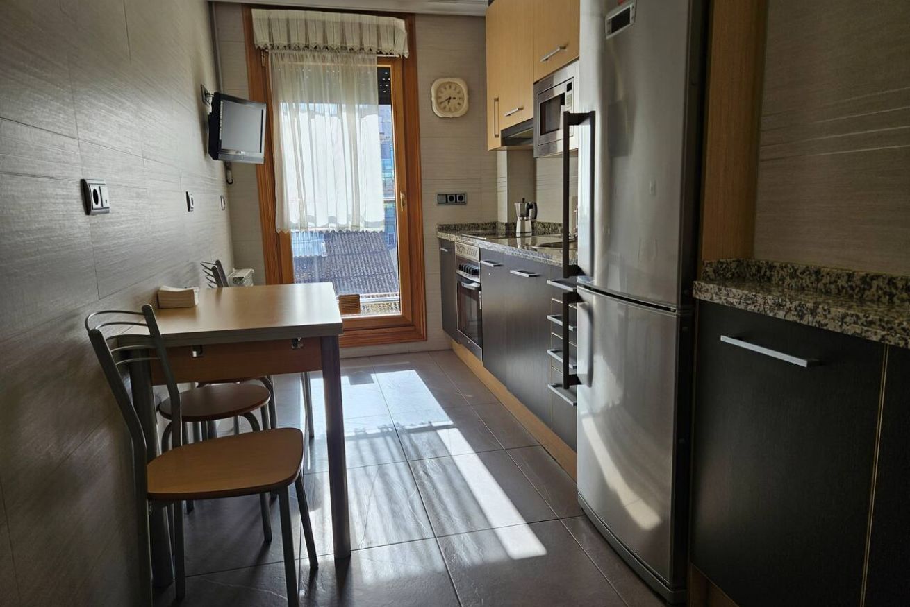 Una cocina con una mesa de comedor, sillas, un refrigerador y un microondas.