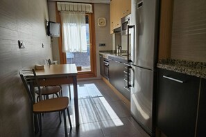 Uma cozinha com mesa de jantar, cadeiras, geladeira e micro-ondas.