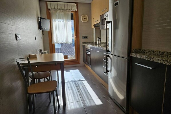Una cocina con una mesa de comedor, sillas, un refrigerador y un microondas.