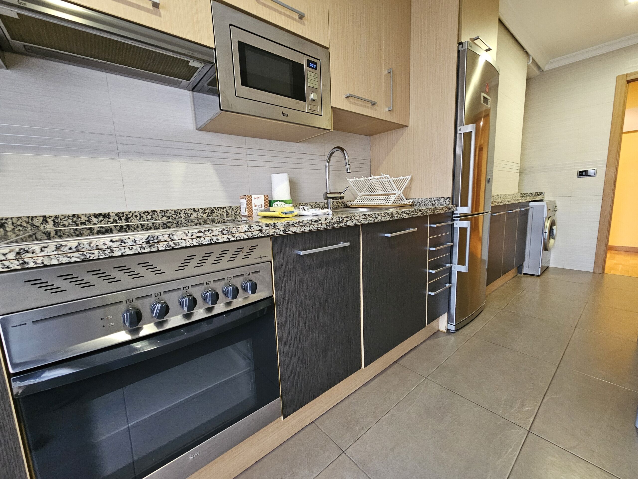 Een koelkast, een magnetron, een oven, kookgerei, borden en bestek