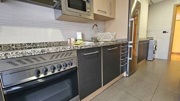 Een koelkast, een magnetron, een oven, kookgerei, borden en bestek