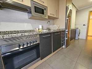 Een koelkast, een magnetron, een oven, kookgerei, borden en bestek