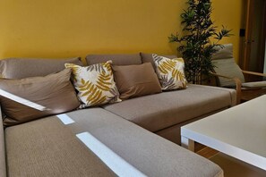 A living room with a sofa, a coffee table, and a plant.