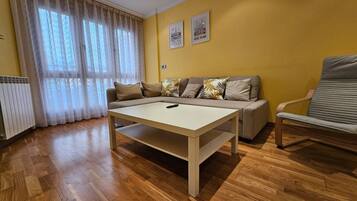 Una sala de estar con sofá, mesa, silla y radiador.
