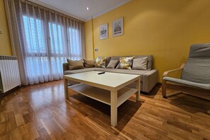 Uma sala de estar com sofá, mesa, cadeira e radiador.
