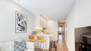 A modern kitchen with white cabinets, a central island, and two bar stools.