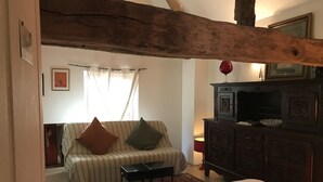 A cozy room with a striped sofa, a small table, a wooden cabinet, and a bed. - Plain Pied Dépendance Chez L'habitant (Bazancourt)