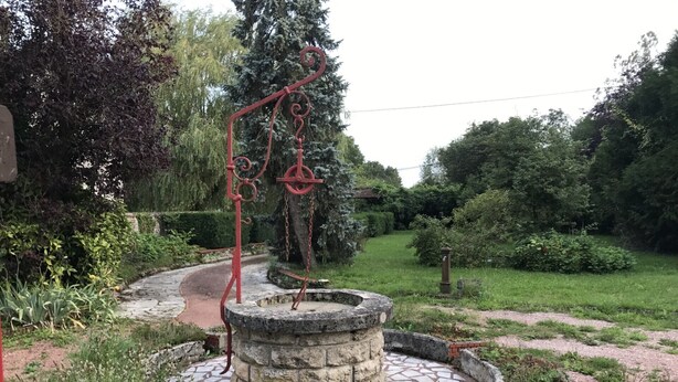 A garden with a circular stone fountain, surrounded by brick edging and a mosaic-tiled path. - Plain Pied Dépendance Chez L'habitant (Bazancourt)