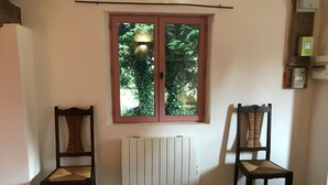 A room with two wooden chairs, a radiator, and a window with a view of greenery. - Plain Pied Dépendance Chez L'habitant (Bazancourt)