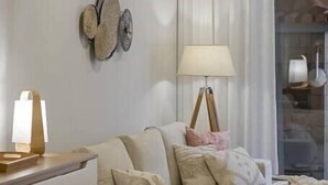 Una sala de estar moderna con un sofá seccional color crema, una mesita de madera y una lámpara de pie.
