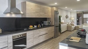 Una cocina moderna con armarios de madera, campana extractora de acero inoxidable, microondas y refrigerador.
