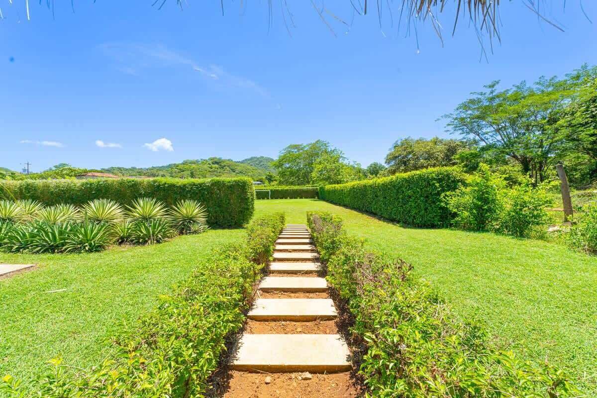 Un sentier qui traverse un jardin bien entretenu, avec des haies et de la pelouse taillées avec soin.