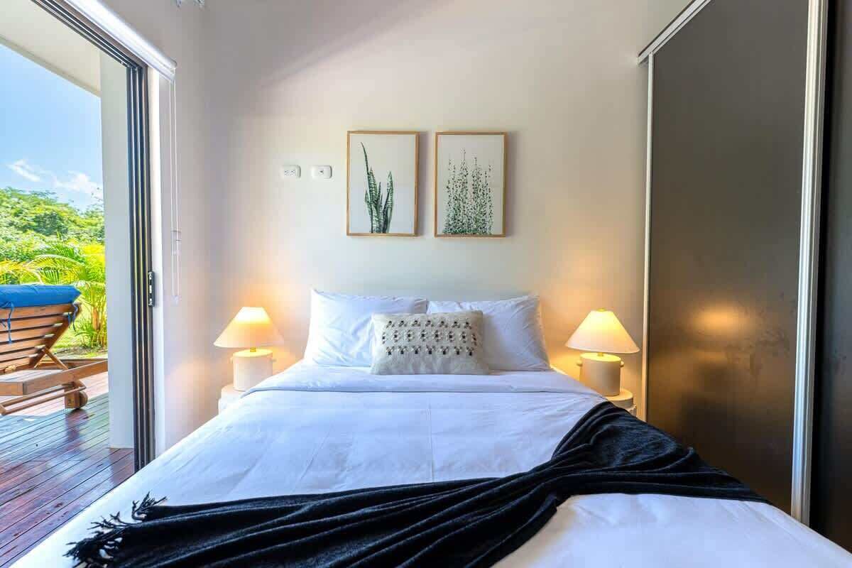 Une chambre à coucher avec un lit, deux lampes de chevet et deux tableaux encadrés accrochés au mur.