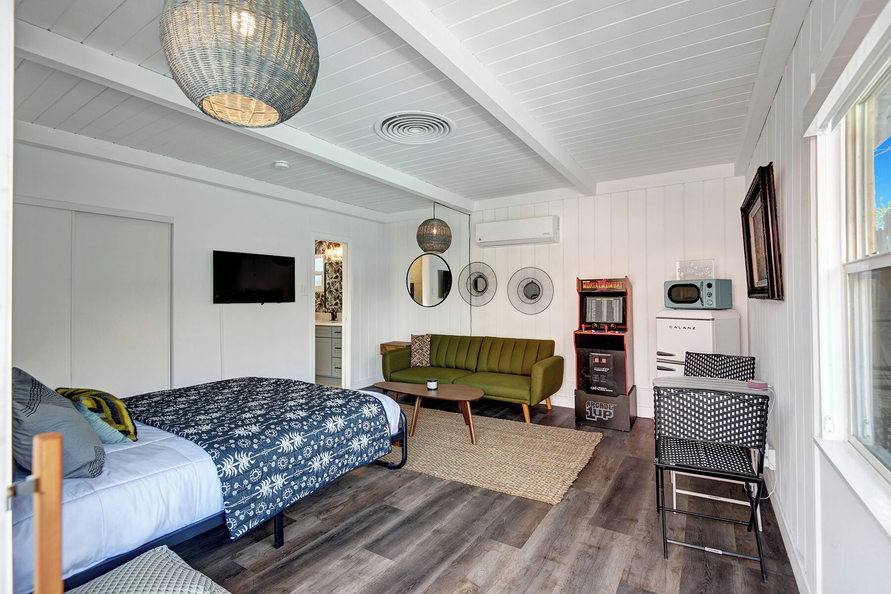 Ein Schlafzimmer mit einem Bett, einem grünen Sofa, einem kleinen Tisch, einem Fernseher und einem Vintage-Radio.