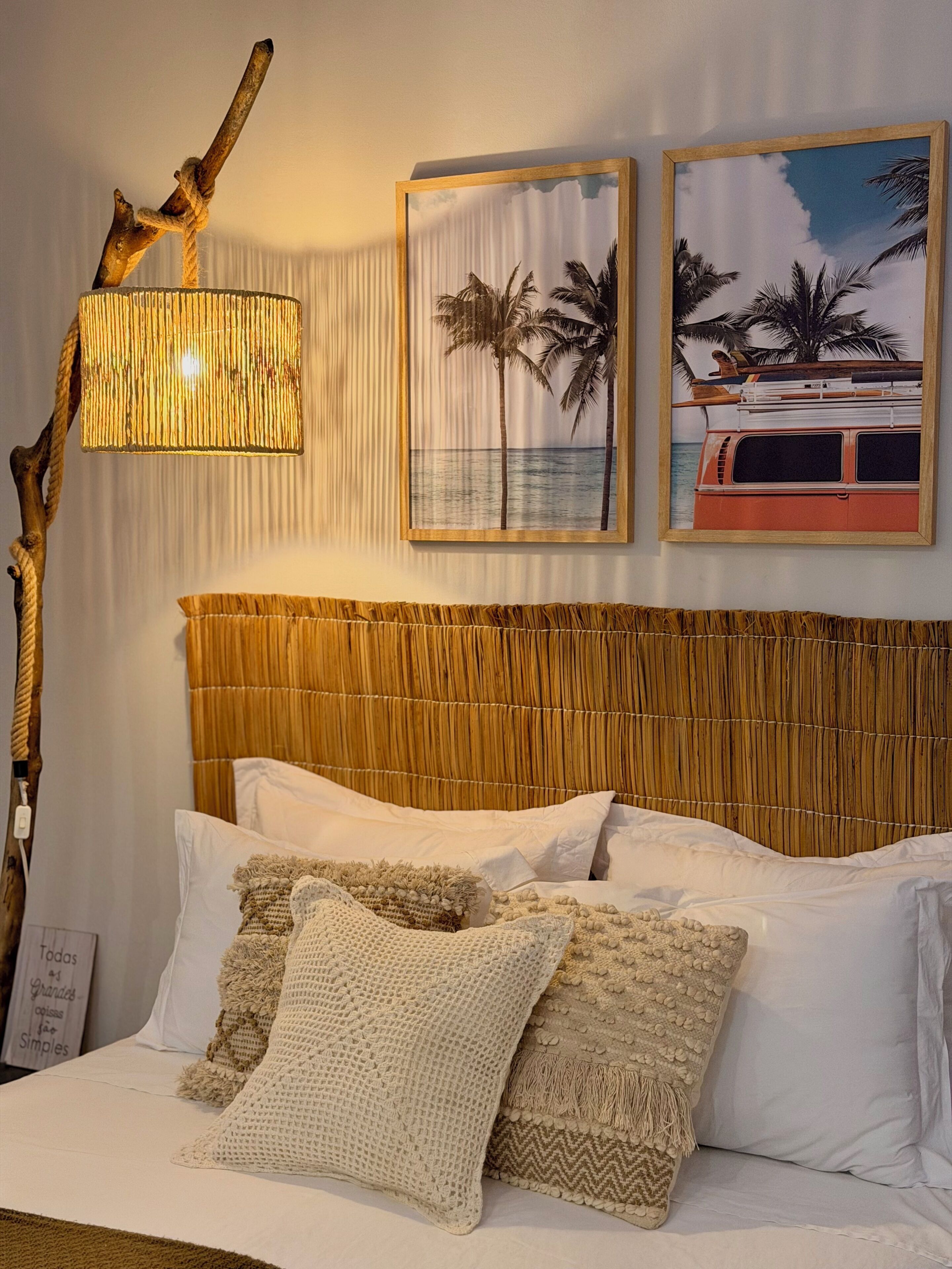 A bed with white linens, a woven headboard, and decorative pillows.