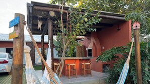 A hammock, wooden chairs, a barbecue area, and a small birdhouse. - Beachfront house with spa! Fire pit / Spa / Hammocks / Gardens / Parking (Morro das Pedras Florianópolis)