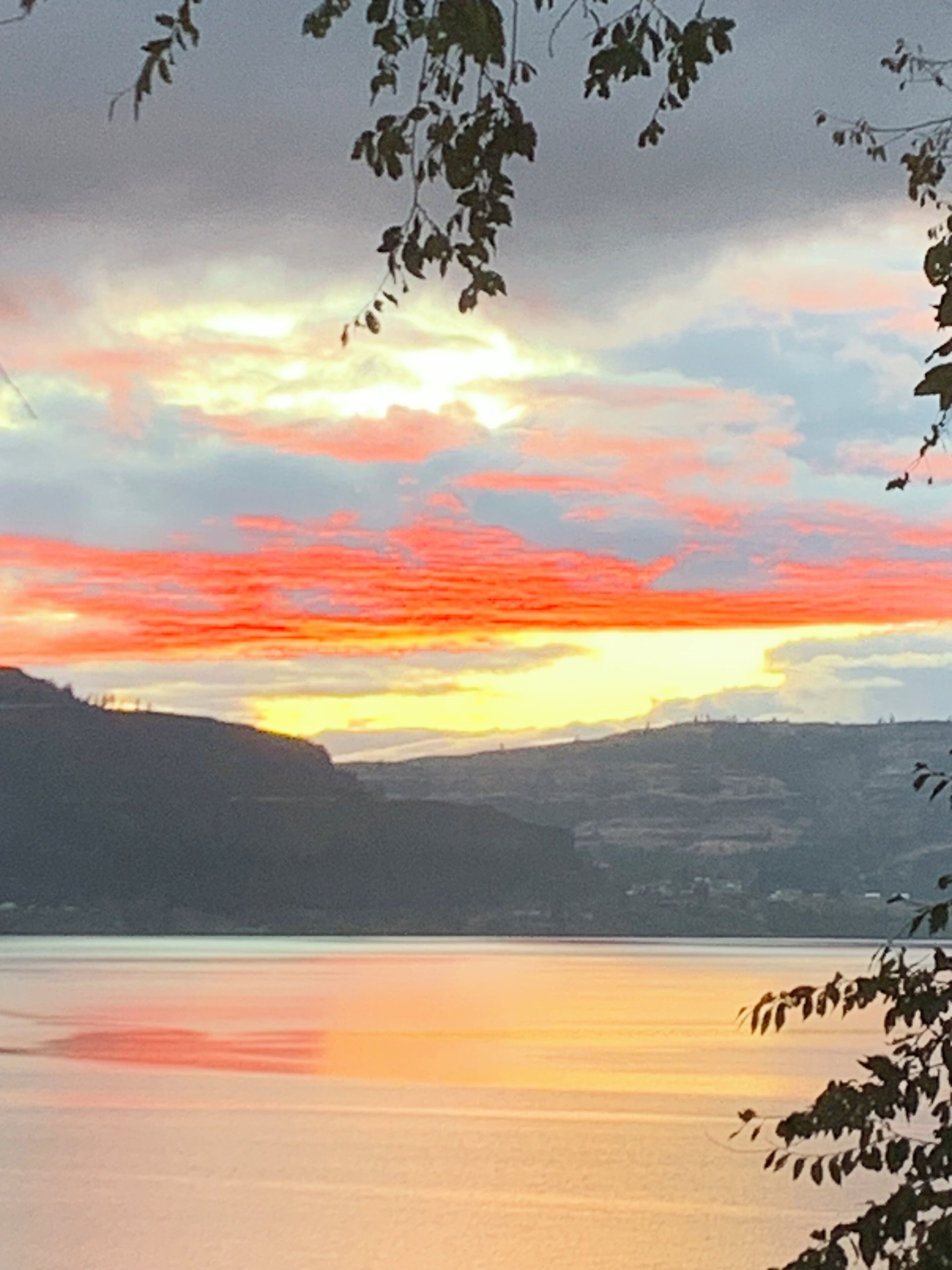 Ein friedlicher See mit einem Sonnenuntergangshimmel, umgeben von Hügeln.