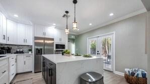 A modern kitchen with white cabinets, stainless steel appliances, and a marble island.