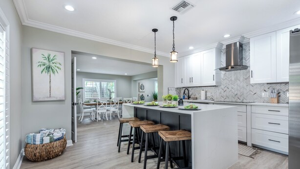 A modern kitchen with a central island, bar stools, and pendant lighting.