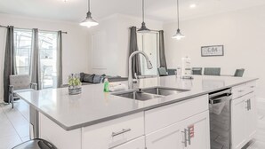 A modern kitchen with a large island, stainless steel appliances, and a dining area with a table and chairs.