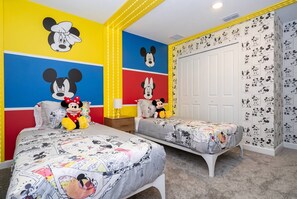 A room with two beds, Mickey Mouse wall art, and a Mickey Mouse wallpaper. - Family Fun at Storey Lake | 4BR Pool Townhome (Kissimmee)