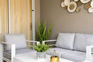 A modern living area with a sofa, a white coffee table, a patterned plant pot, and a decorative wall piece. - Family Fun at Storey Lake | 4BR Pool Townhome (Kissimmee)
