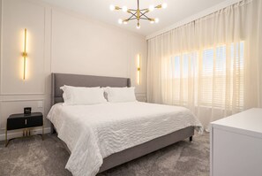 Un dormitorio con cama, mesitas de noche, escritorio y candelabro.