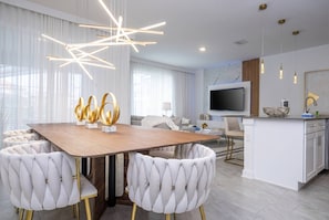 Una cocina moderna con una isla central, armarios blancos y un televisor de pantalla plana.
