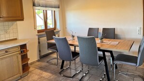 A modern kitchen with a wooden ceiling, a dining table with four chairs, and a window with curtains. - ~straubings Großes Apartment~ (Straßkirchen)