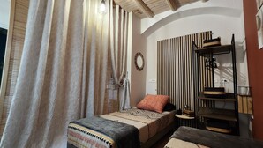 Una camera da letto con un letto, un comodino, uno specchio, una parete a righe e uno scaffale con cesti.