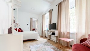 Ein modernes Hotelzimmer mit einem Bett, einem Fernseher, einem kleinen Tisch und einem roten Sessel.