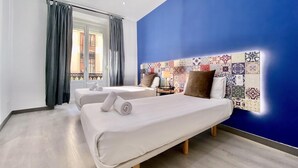 A hotel room with two beds, a blue accent wall, and a patterned tile headboard.