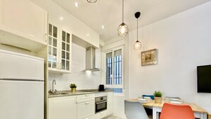 A modern kitchen with white cabinets, a built-in oven, and a dining area with a wooden table and chairs.