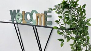 A modern reception desk with a 'Welcome' sign and a potted plant.