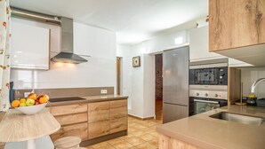 A modern kitchen with a central island, stainless steel appliances, and a wooden cabinet. - Stunning home in Torrox (Torrox)