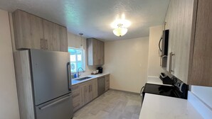 A modern kitchen with wooden cabinets, stainless steel appliances, and a white countertop. - Centrally located home in the heart of Twin Falls.  (Twin Falls)