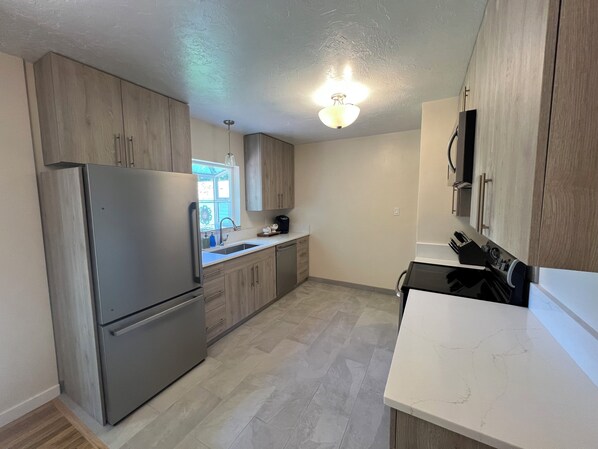 A modern kitchen with wooden cabinets, stainless steel appliances, and a white countertop.